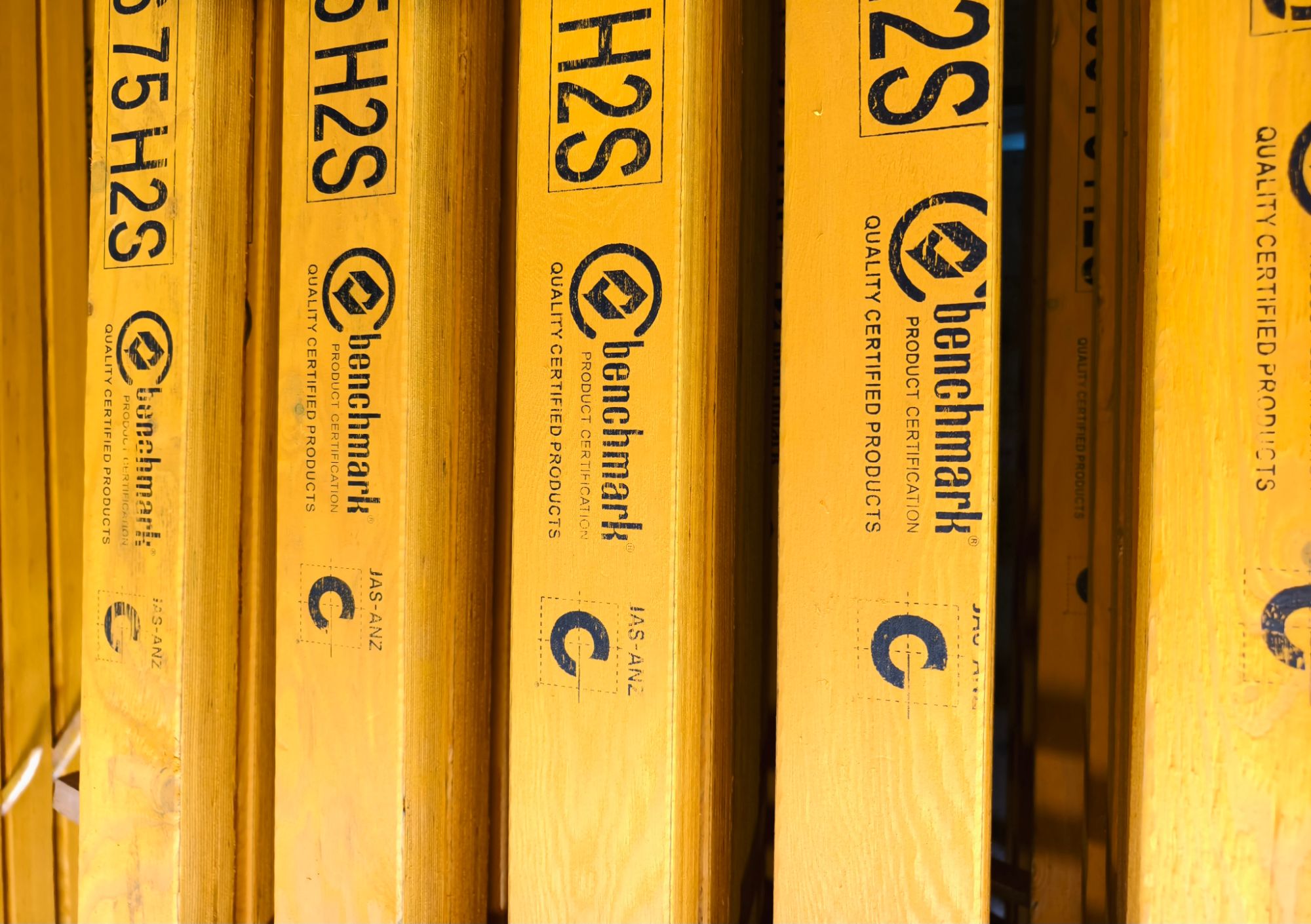 Stack of H2S treated LVL beams stamped with Benchmark quality certification marks